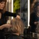 Hairstylist al lavoro davanti a uno specchio con immagini digitali generate dall’intelligenza artificiale.