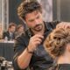 Hairstylist italiano concentrato durante una gara ufficiale di acconciatura, con giuria sullo sfondo.