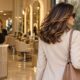 Donna in uscita dal salone con piega castana lucida; la parrucchiera resta alla reception
