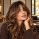 Donna con curtain bangs morbide e capelli lunghi in un salone dall’atmosfera autunnale