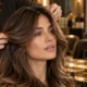 Hairstylist examining long brunette hair during a professional salon consultation