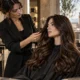 Parrucchiera che valuta i capelli lunghi e lucidi di una cliente in un salone professionale con vista su Firenze