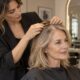 Parrucchiera valuta la densità dei capelli di una cliente over 50 in salone