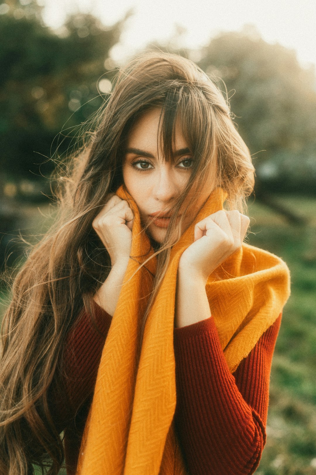 Woman with long hair and a soft face-framing fringe in autumn