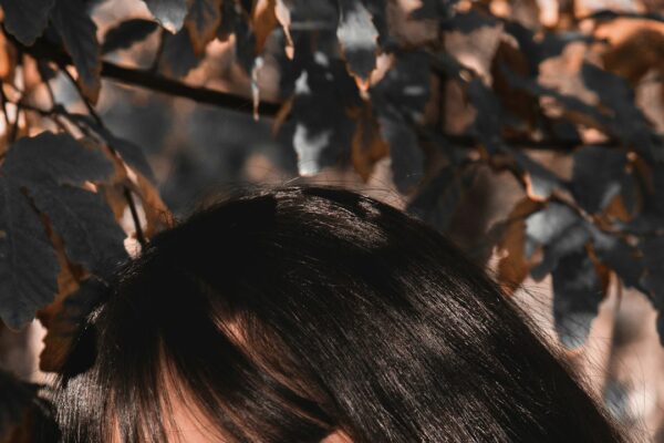Woman with soft fringe and long hair among autumn leaves