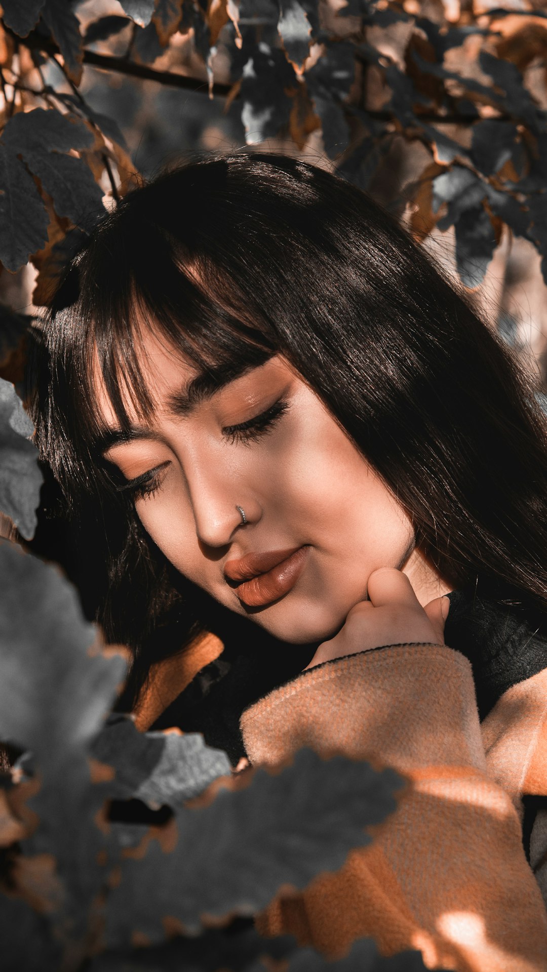 Woman with soft fringe and long hair among autumn leaves