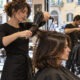 Stylist giving a round-brush blow-dry in a busy Italian neighbourhood salon