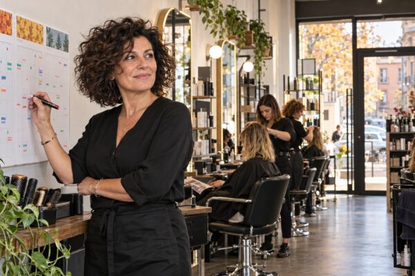 Titolare di salone pianifica ottobre, novembre e dicembre davanti al calendario con il team al lavoro