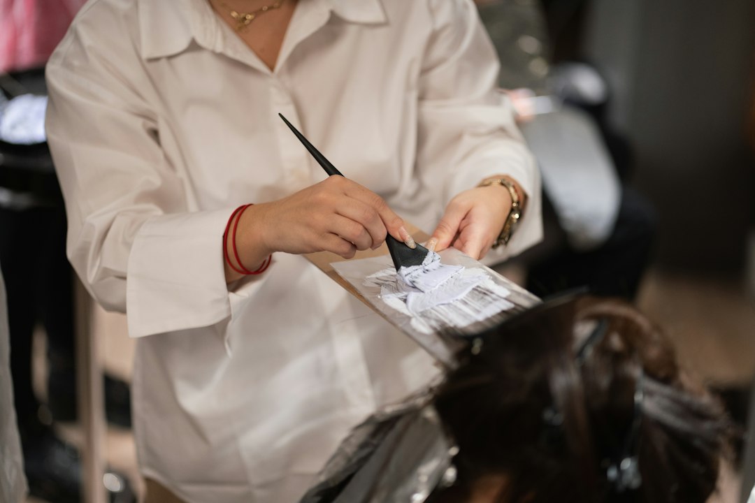 Parrucchiera taglia i capelli a una cliente seduta in salone.