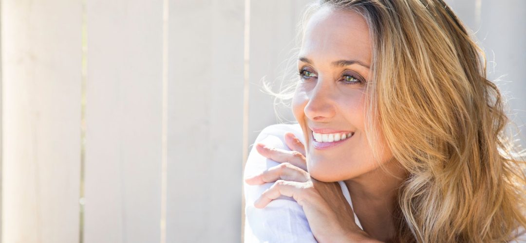 Donna over 40 con capelli biondi luminosi e sorriso naturale, esempio di look fresco e giovanile.