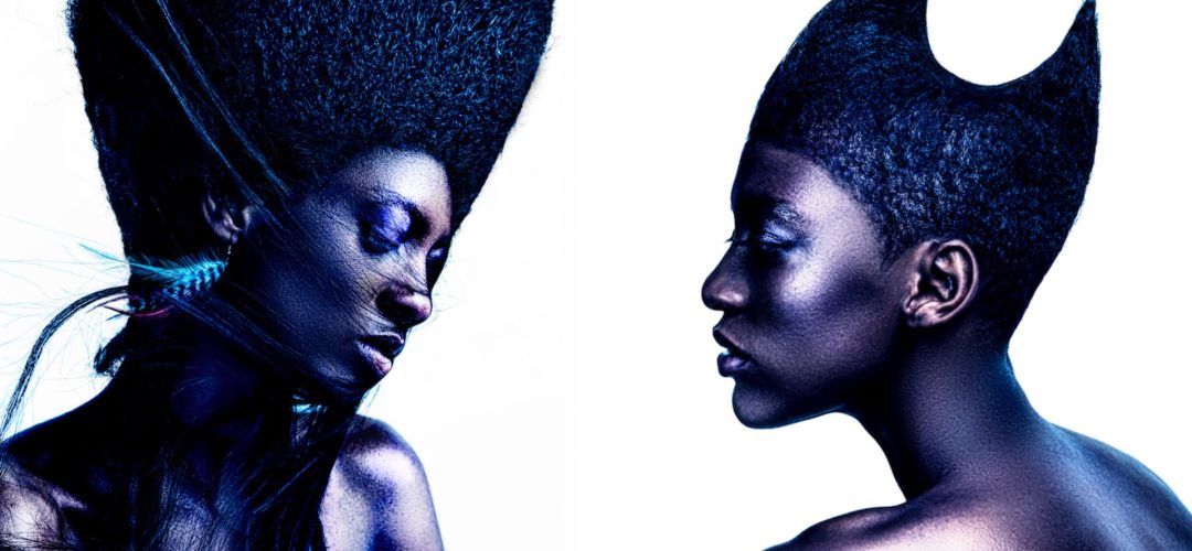 Due modelle con capelli afro scolpiti in forme geometriche ispirate all’arte di Barbara Hepworth, fotografate su sfondo bianco.