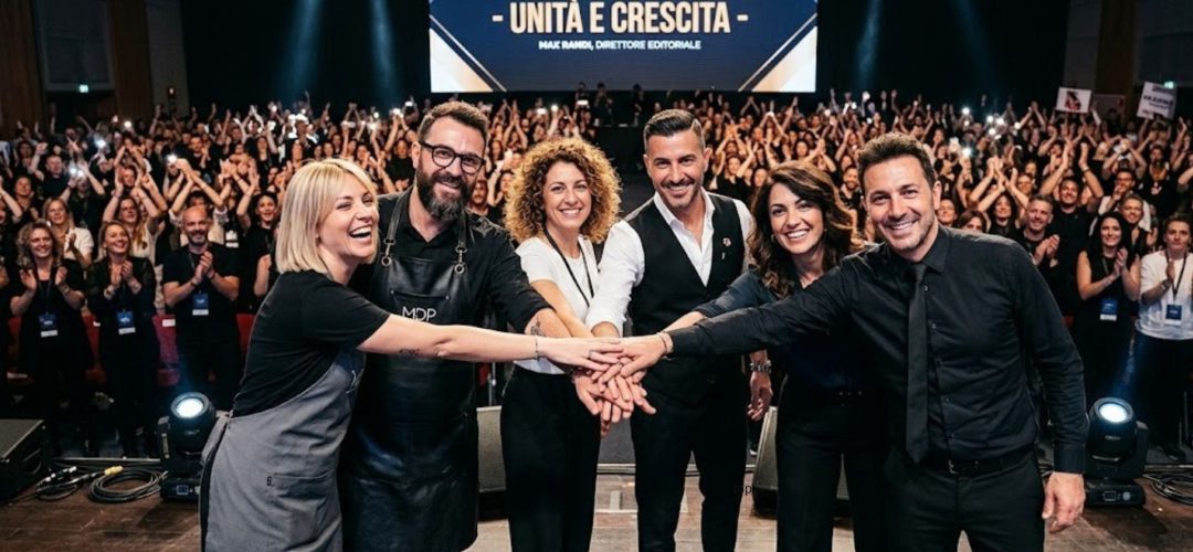 Un gruppo di sei parrucchieri e leader del settore hair & beauty unisce le mani sul palco principale del MDP Congress in un gesto di unità. Sullo sfondo, un grande schermo a LED mostra il testo "- UNITÀ E CRESCITA -" e un auditorium immenso e gremito di migliaia di colleghi applaude e scatta foto.