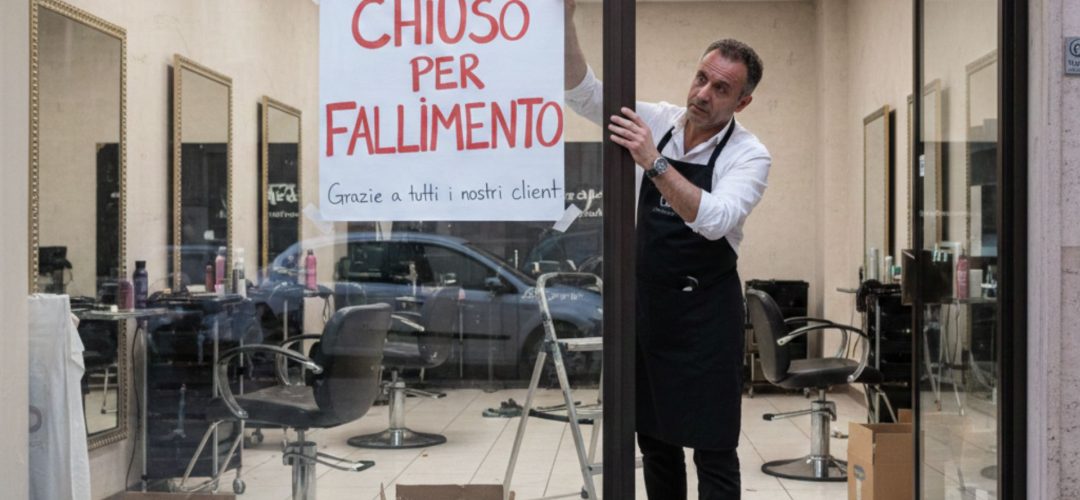 Parrucchiere sconfortato appende il cartello "Chiuso per fallimento" sulla vetrina del suo salone di bellezza, simbolo della crisi del settore.