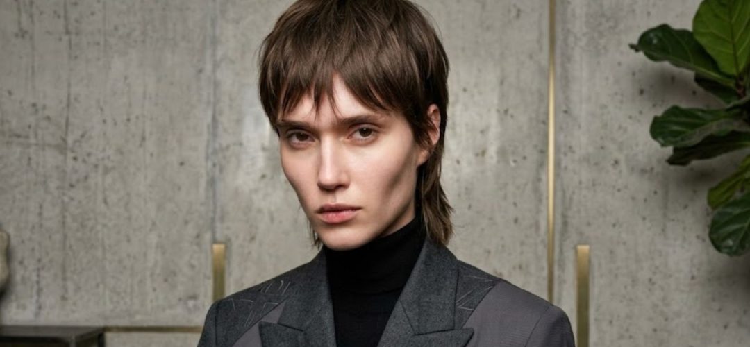 Modella con taglio corto sfilato Trixie Cut e giacca grigia con spilla MDP.