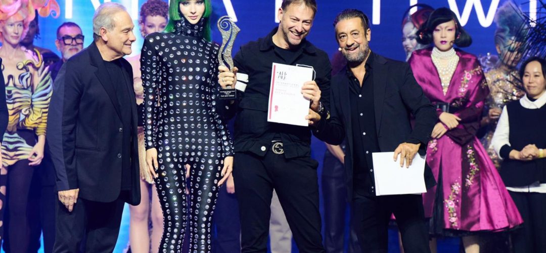 Matteo Susini premiato sul palco del Visionary Award 2024, affiancato da una modella con i capelli verde lime e altri partecipanti, mentre riceve il trofeo per la categoria Cut and Color.