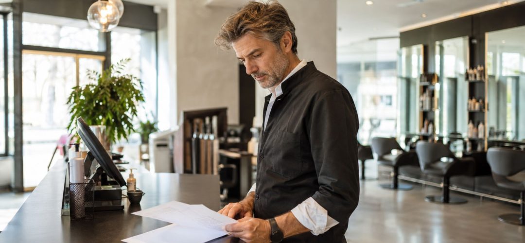 Titolare di un salone di parrucchiere controlla alcuni documenti alla reception
