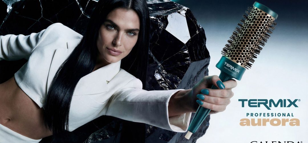 Modella con capelli lisci scuri regge una spazzola termica Termix Aurora Professional con manico verde acqua e setole dorate, sfondo scuro con roccia effetto specchio, logo Calenda importatore ufficiale